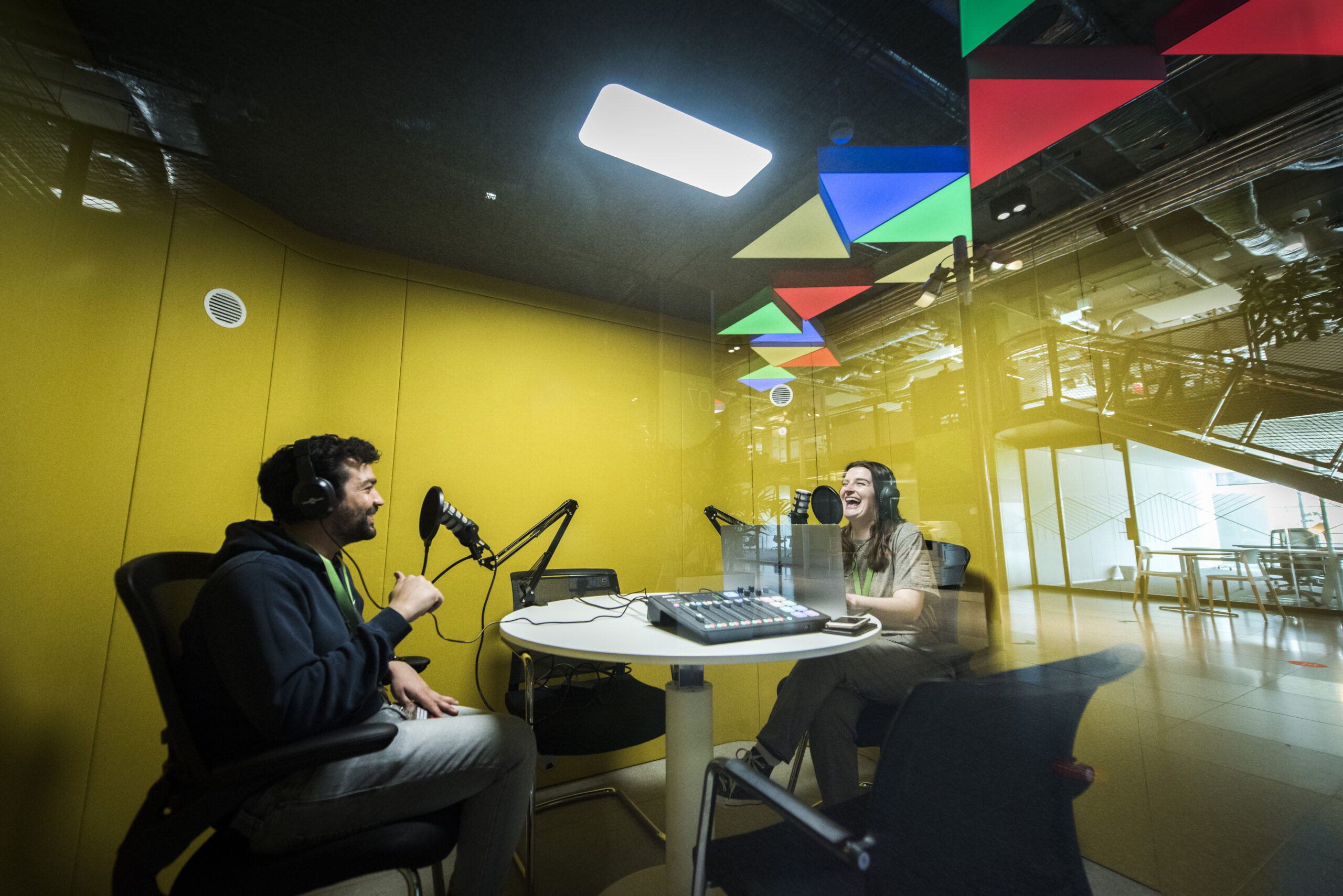 Two people recording a podcast in a booth at Plexal