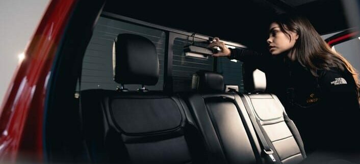 A canopy employee attaches a sensor to the inside of the rear window of a pickup truck.