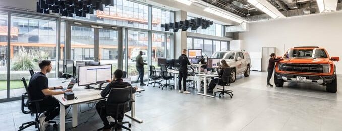 A full shot of Canopy's vehicle workshop, showing people at desks and vehicles in open spaces.