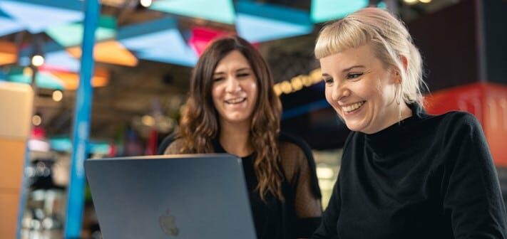 Two canopy employees work at a laptop in Plexal.