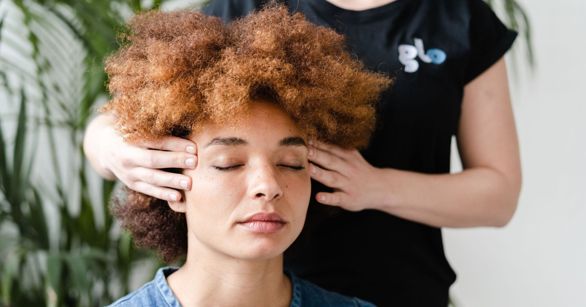 A woman receiving a head massage from a Glo massage therapist